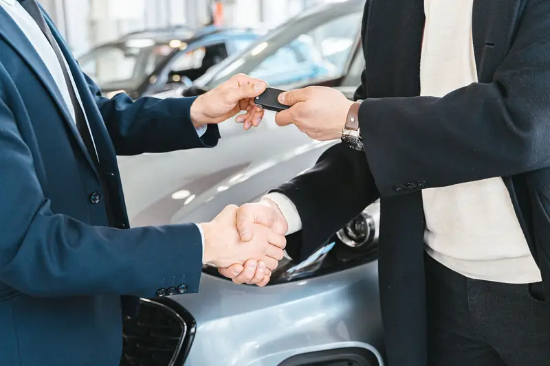 Vendedor entregando a chave do carro ao cliente